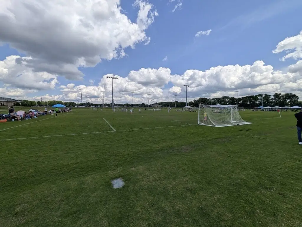 Youth soccer fields and a goal beneath a bright sky filled with clouds